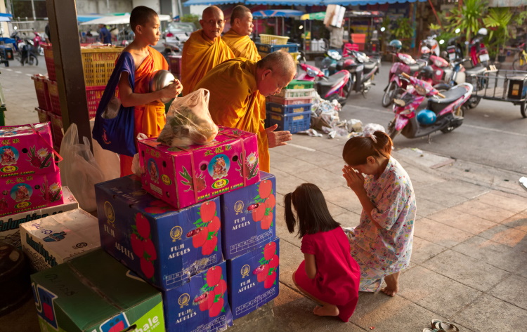 Woman And Child Making Offerings To Thailand Monks