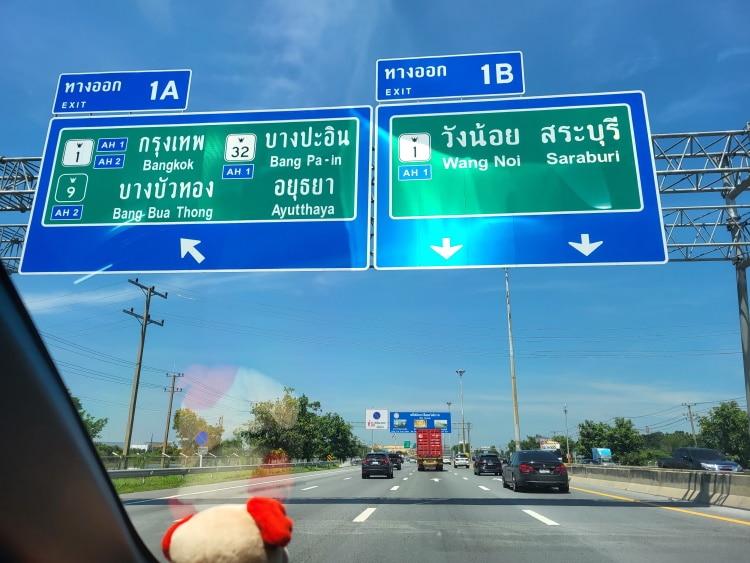 Thailand Road Signs Above Cars Through A Car Window