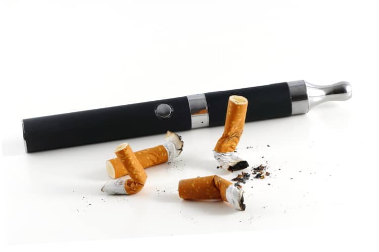 Cigarette Ends Next To A Vape Pen On White Background