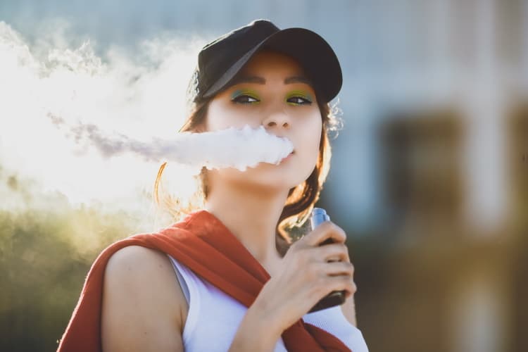 Preety Asian Lady Vaping An Ecig And Blowing White Smoke Out