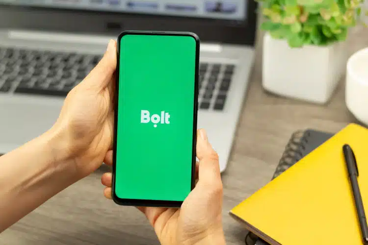 Bolt Taxi Application On Mobile Phone In Front Of Laptop Computer At A Desk