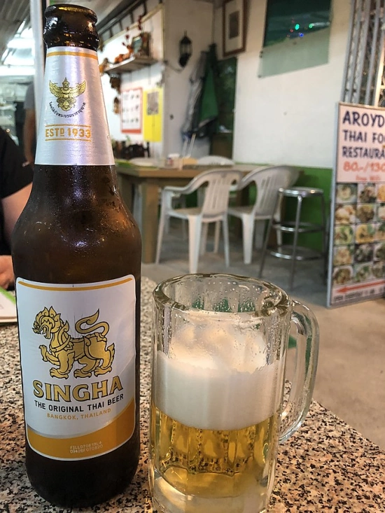 Singha Beer Bottle Next To A Glass Of Beer In Thai Restaurant