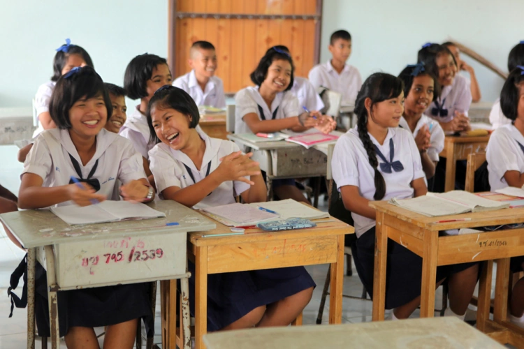 Young Thai Students At Their Desks At A Thailand School Smiling And Laughing