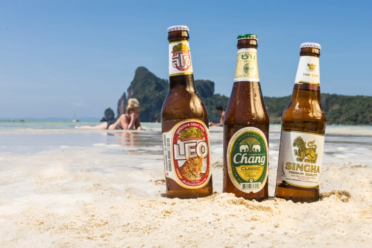 A Bottle Of Chang, Singha And Leo Beers On A Thailand Beach
