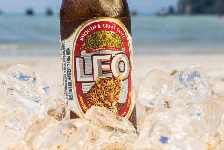 A Bottle Of Leo Thailand Beer In Sand On Beach Surrounded In Ice