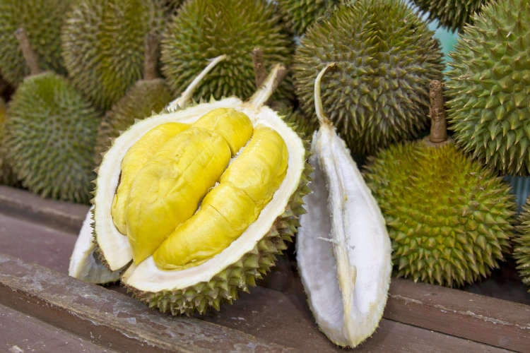 A Collection Of Thailand Durian Fruit With One Cut Open In Half On Slats Of Wood