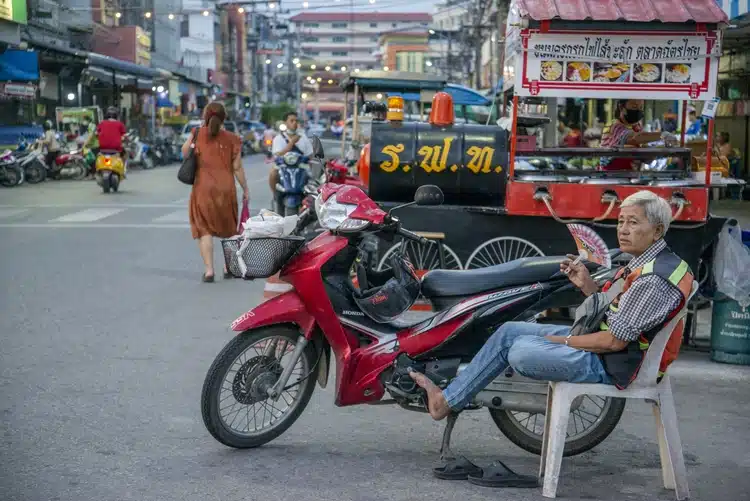 A Thai Street Food Stall And Motobike Taxi Driver Sitting Down At The Nightmarket In The City Of Hua Hin 