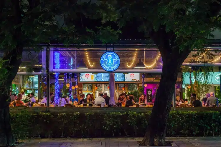 Craft Bar And Restauramt On Soi 23 In Bangkok With A Garden Area And People Drinking