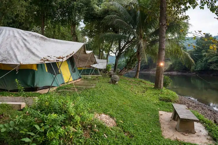 Camping Tent Pitched At The Side Of The River Kwai In Kanchanaburi