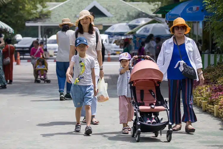 Family In Thailand Walking With Baby Buggy And Children